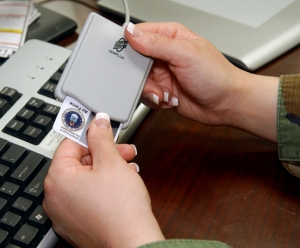 Hands inserting a CAC card into a CAC reader